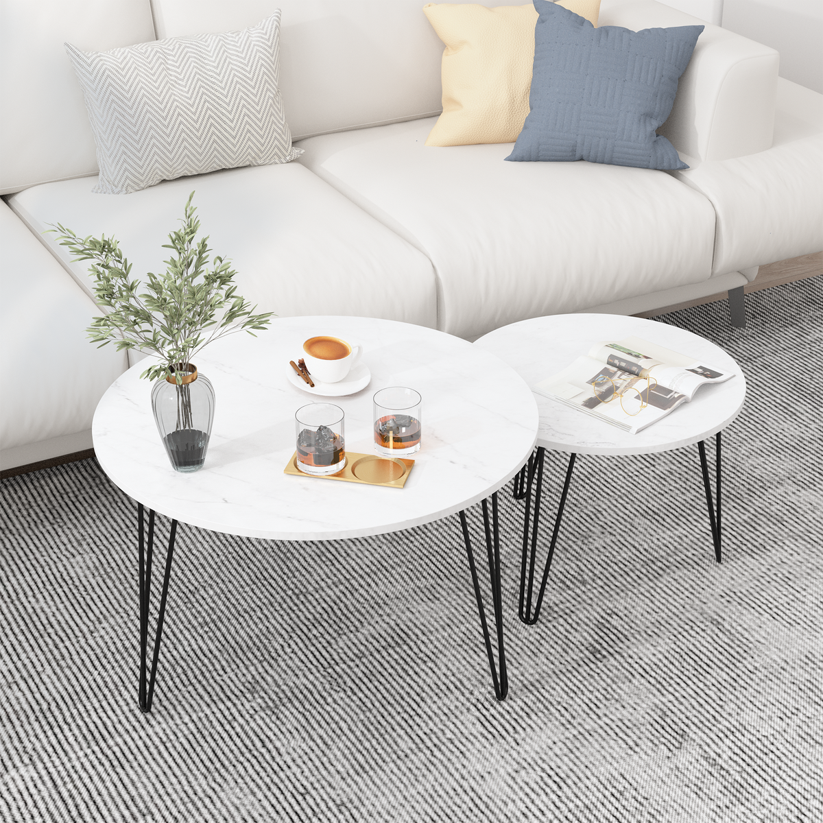 Two round nesting coffee tables with white marble-look surfaces and black metal legs