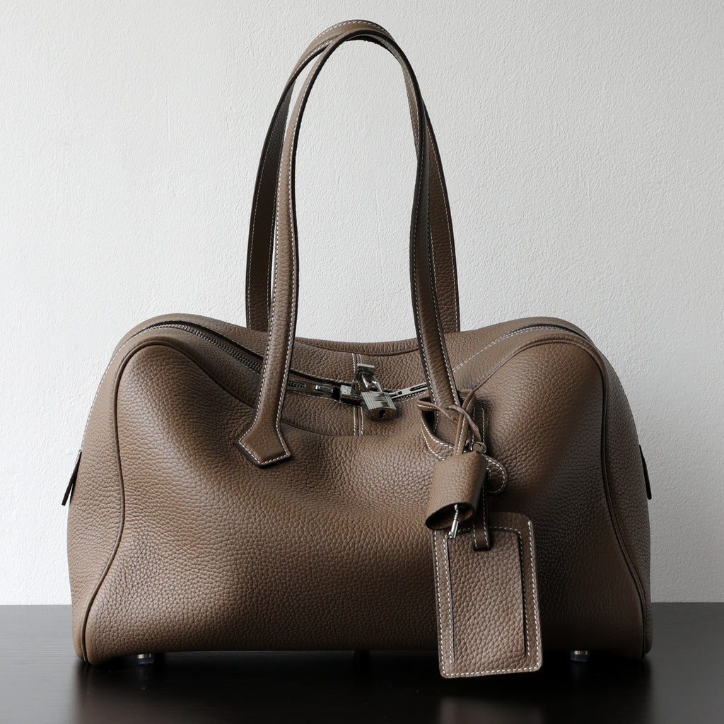 Taupe leather-look hand-held crossbody bag with top handles, front zipper, and tag