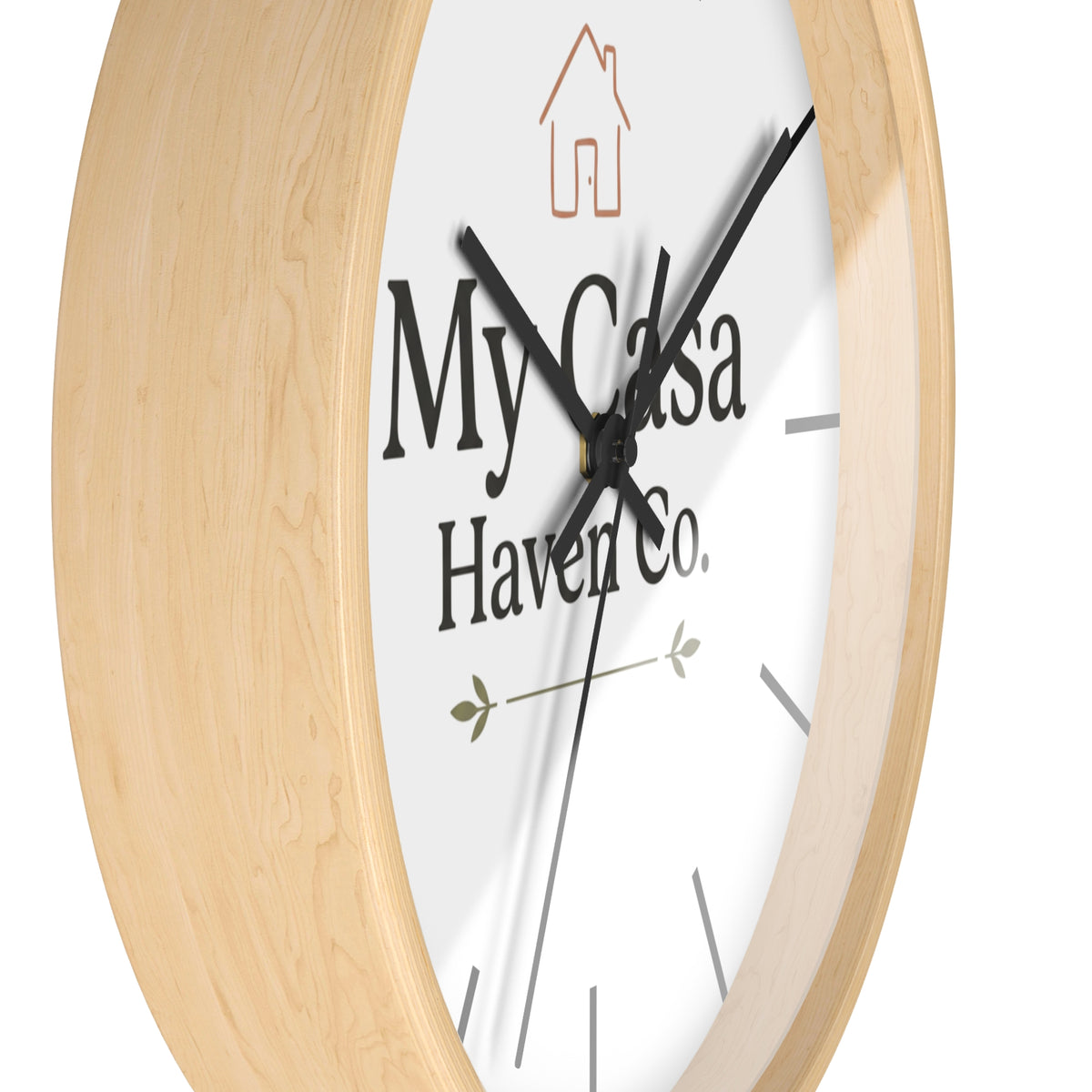 Round wall clock with light wood frame and white dial, black hands and logo text.