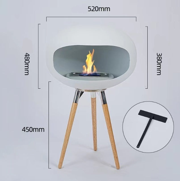 Light gray round ethanol fireplace bowl on three wood tripod legs, flame centered in tray.