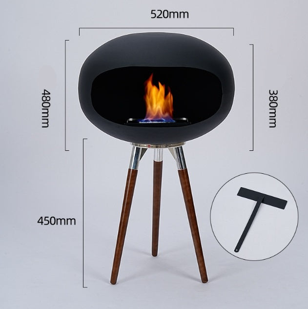 Black round ethanol fire bowl stand with chrome ring accents and three wood tripod legs.