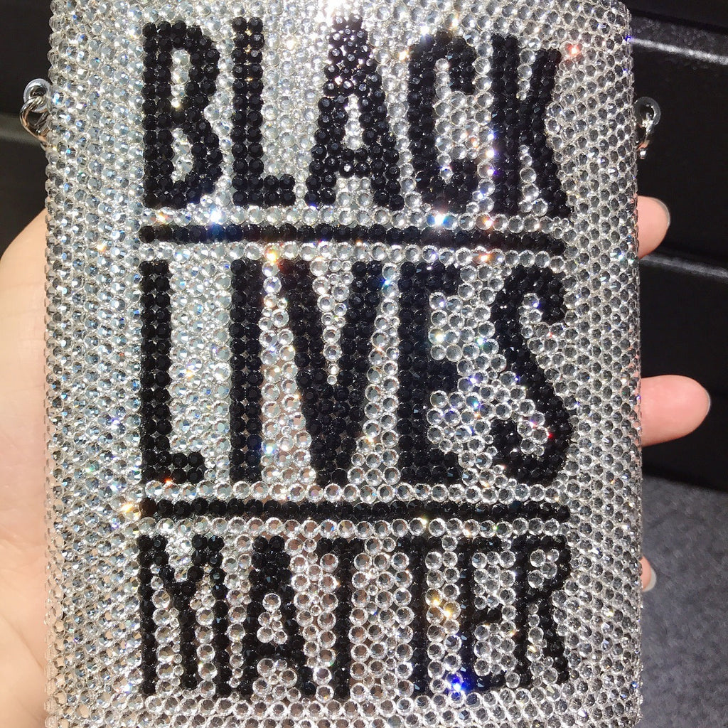 Rhinestone mini bag held close-up, “BLACK LIVES MATTER” text on glittering surface