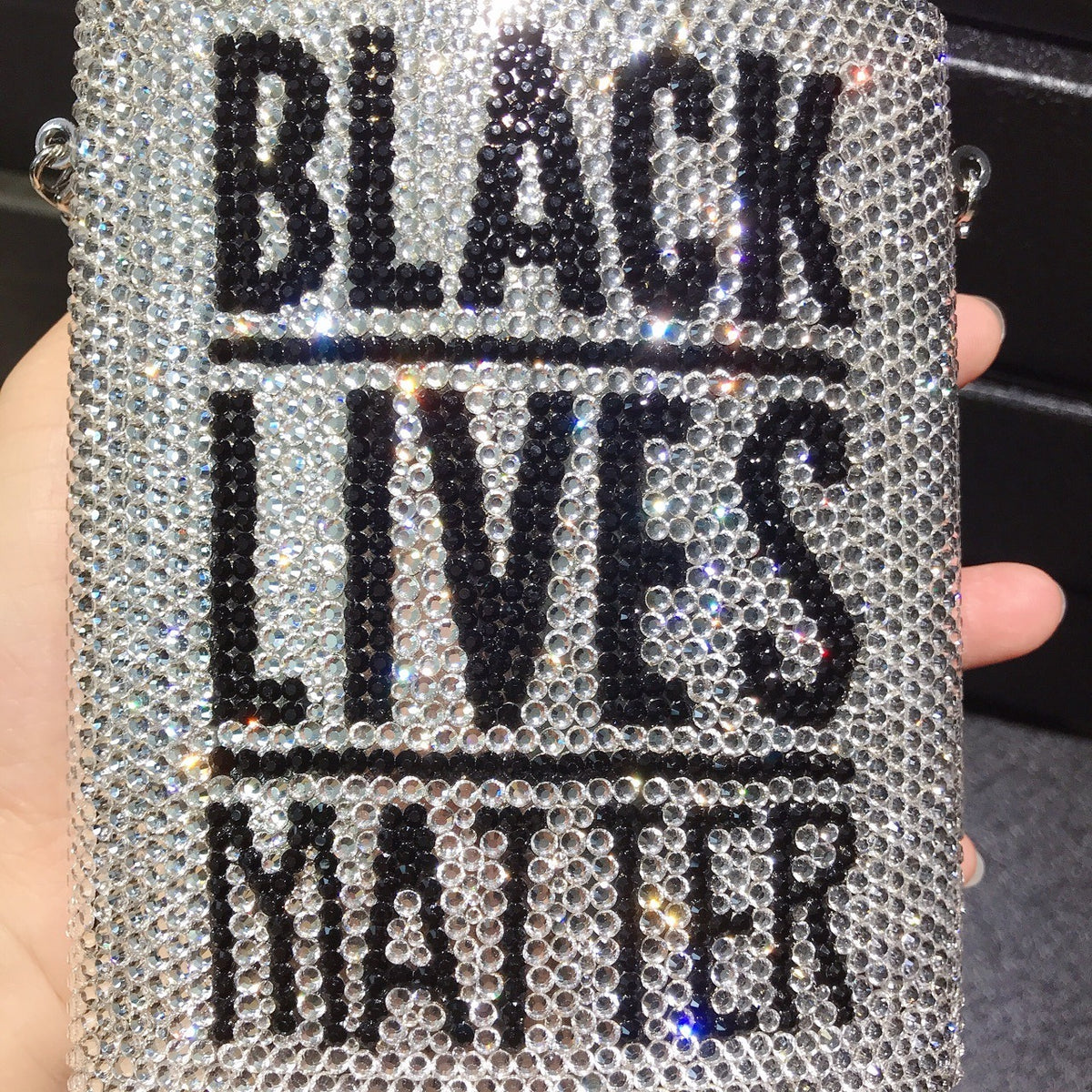 Rhinestone mini bag held close-up, “BLACK LIVES MATTER” text on glittering surface