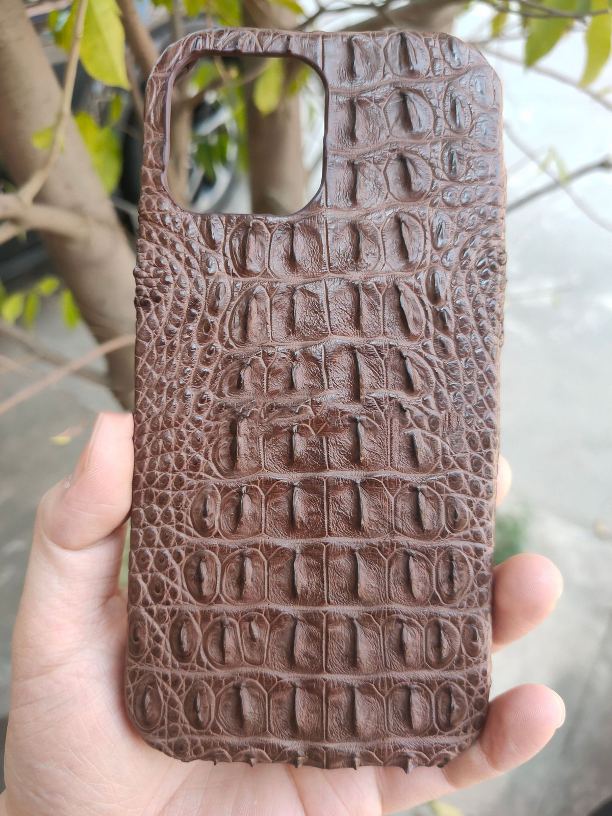 Brown crocodile leather phone case back with embossed scale texture and cutouts
