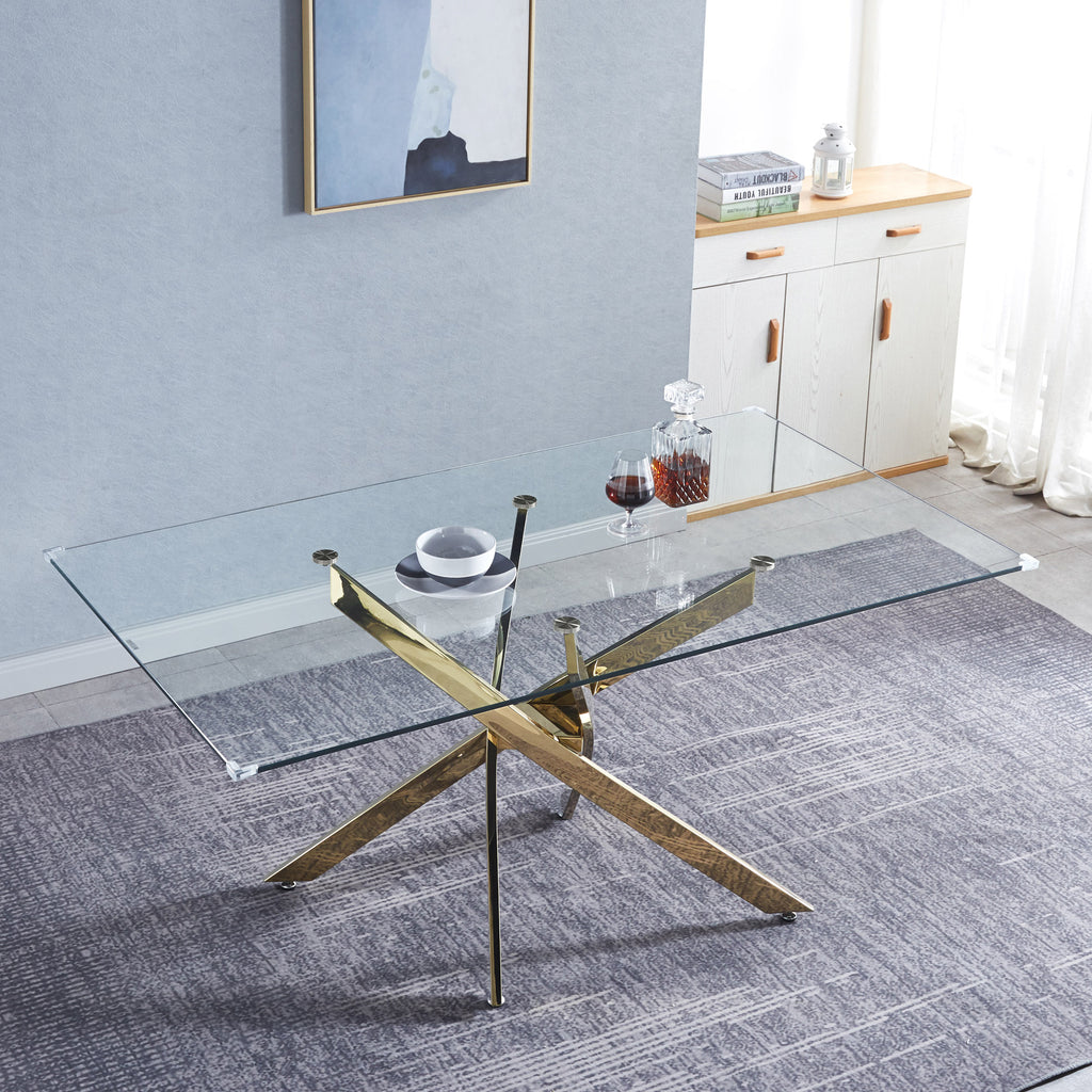 Rectangular glass dining table with gold X base and clear tempered glass top.