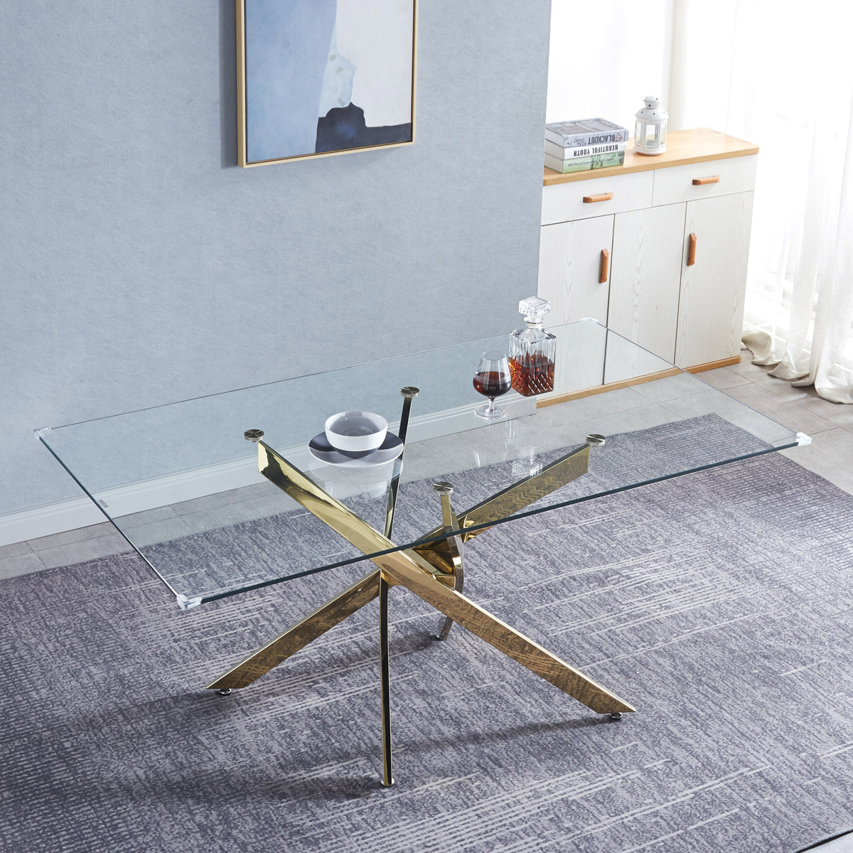 Rectangular glass dining table with gold X base and clear tempered glass top.
